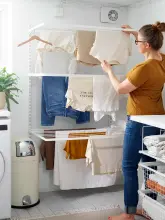 Kobieta rozwieszająca ubrania na rozkładanej suszarce