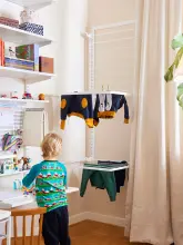 Dziecko bawiące się w pokoju i suszące się ubrania